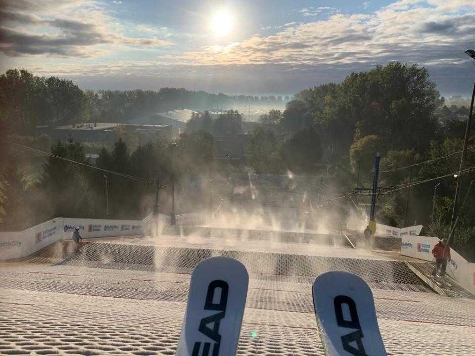 De buitenpiste van bovenaf met ski's op voorgrond en mooie zon