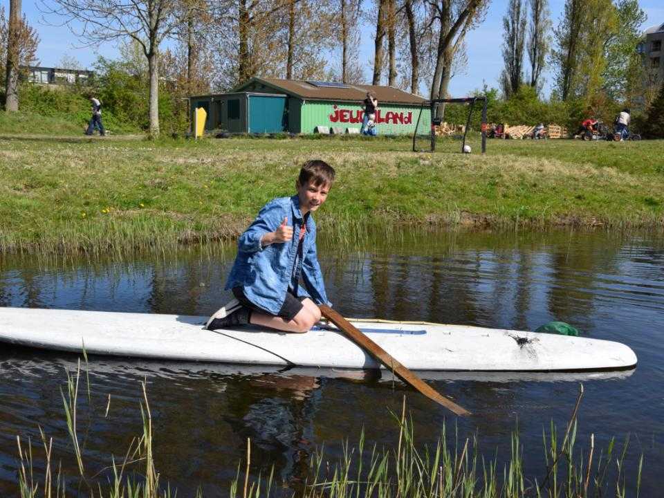 Kind op surfplank op water bij jeugdland hoofddorp