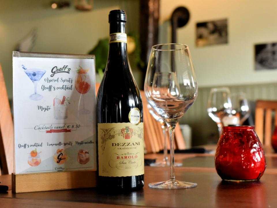 Fles wijn met menukaart op tafel bij Geoff's