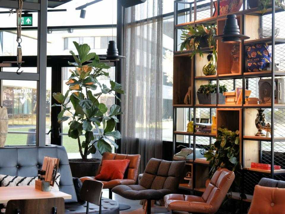 Lobby met veel ramen en relax banken en stoelen van hotel Moxy Amsterdam