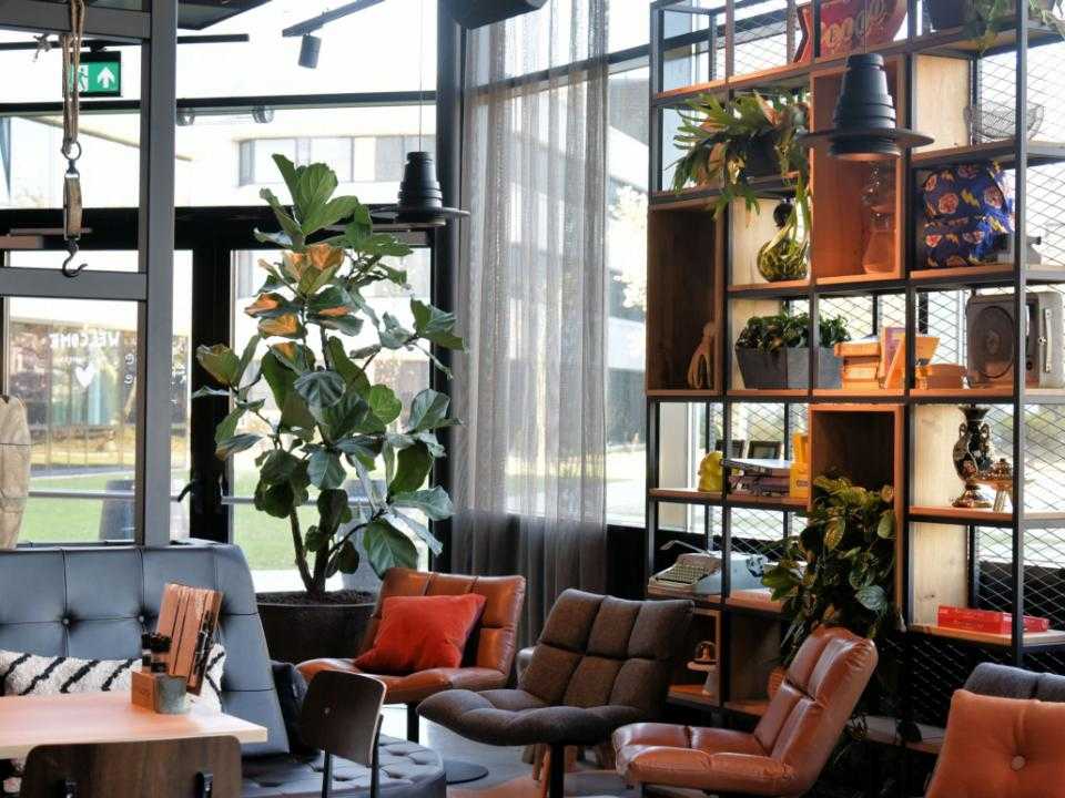 Lobby with many windows and relaxing sofas and chairs of hotel Moxy Amsterdam