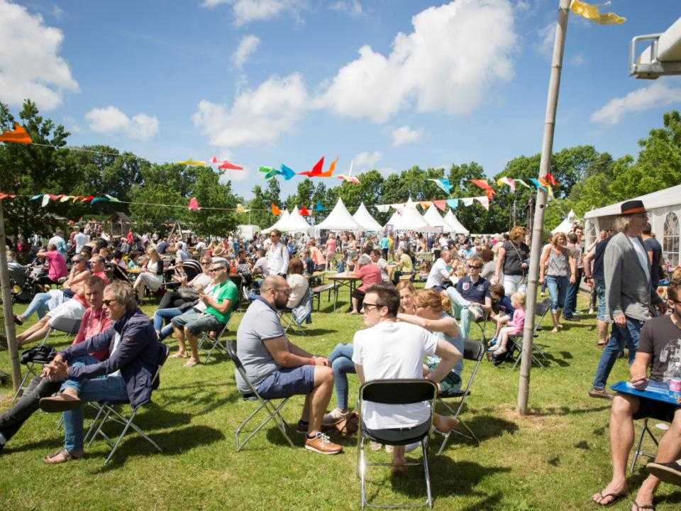Festival op Olmehorst met mensen op zitjes in het gras