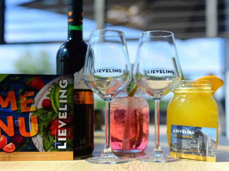 Sfeerbeeld met 2 wijnglazen en paar andere drankjes op tafel en menukaart