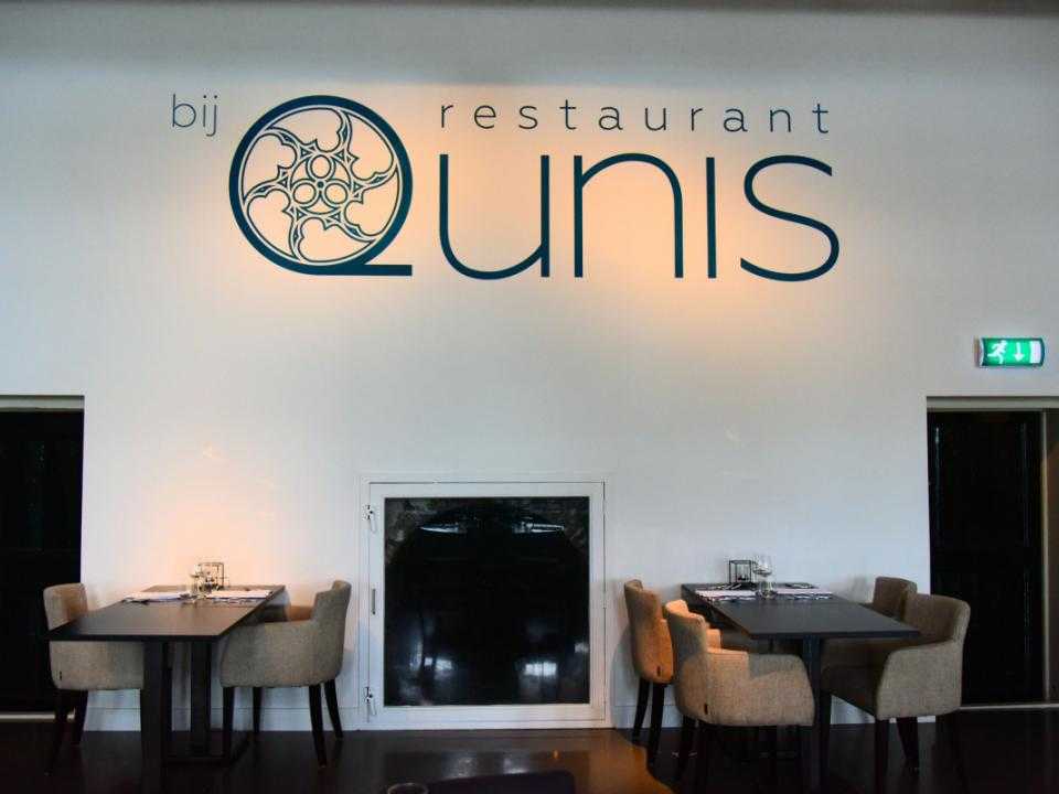 Logo Qunis op witte muur in restaurant