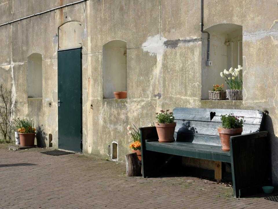 Buitenkant Fort Penningsveer met bankje en planten tegen de muur