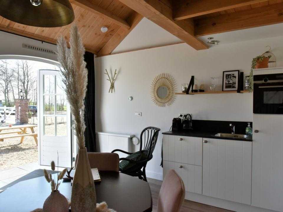 Interieur met eettafel en keuken en openslaande deuren naar buiten terras Noxem Bed & Breakfast