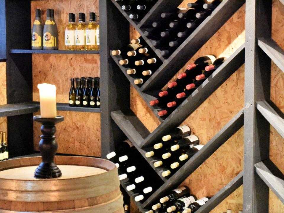 Wijnrek met flessen wijn bij restaurant Nobel