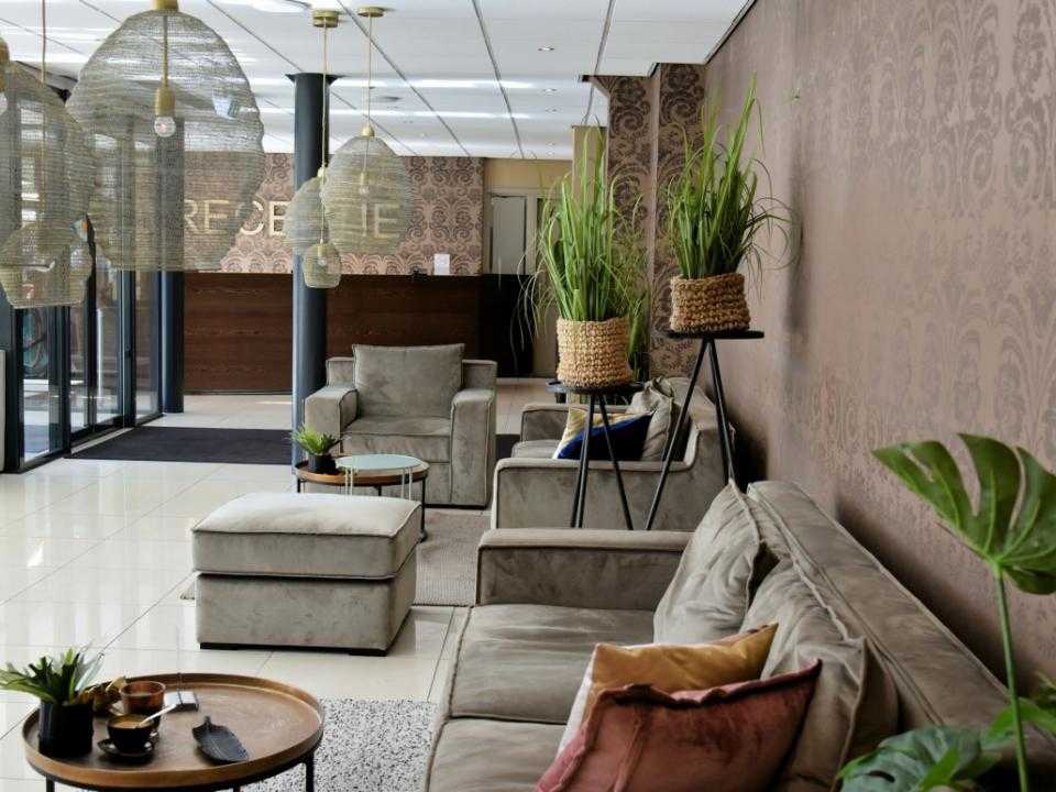Lobby met bank en planten van hotel restaurant de beurs