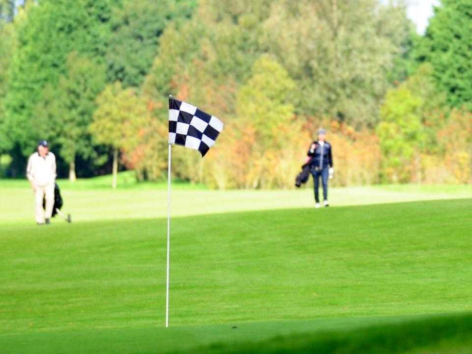 Hole vlag op golfbaan met 2 golfers op de achtergrond