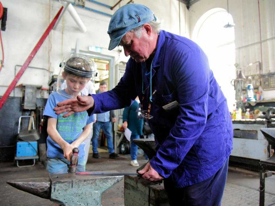 Jongen en vrijwilliger aan het ijzer smeden in het Stoomgemaal Halfweg