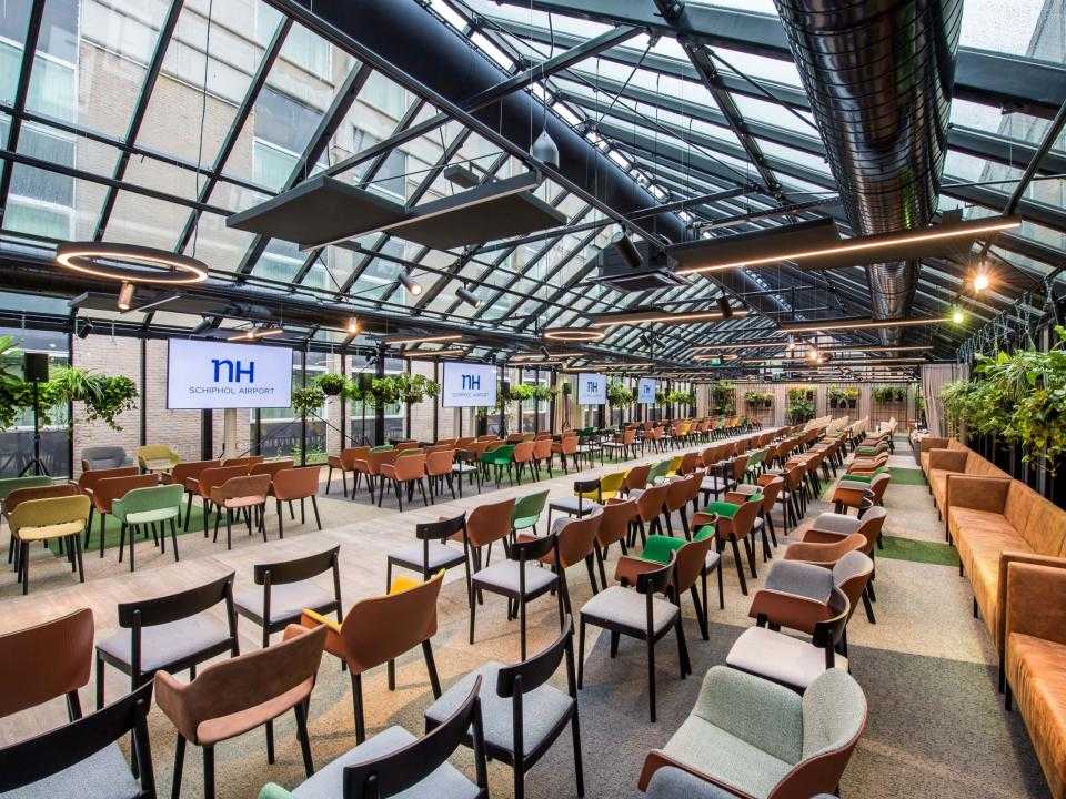 Het interieuw van Greenhouse, een soort kas vol met stoelen en planten, van NH hotel