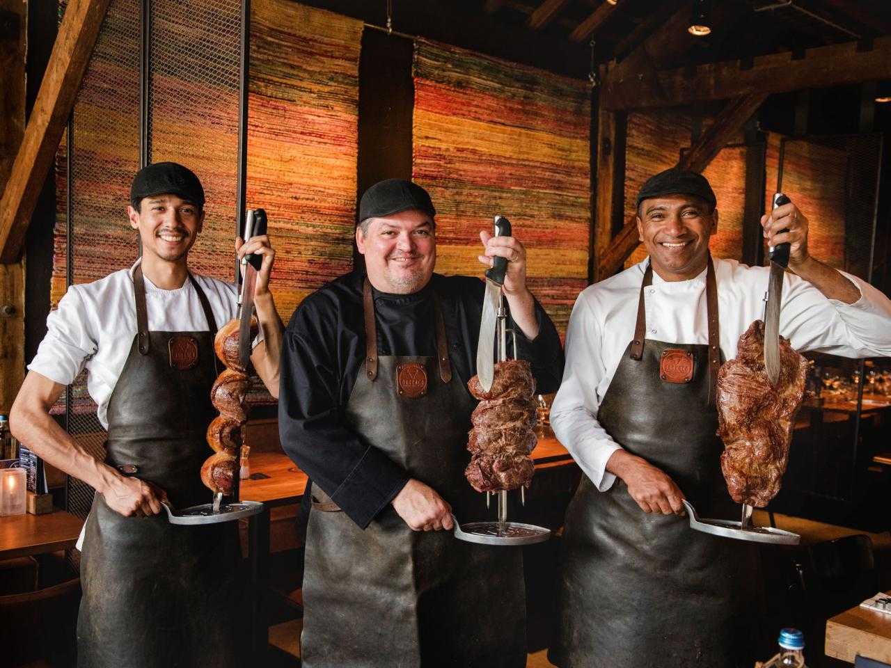 3 mannen met spies vlees bij restaurant Barraca