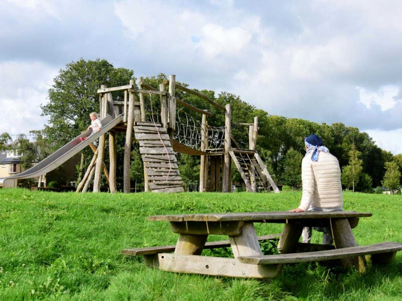 Vrouw op picknickbank met zicht op speeltoestel in park vijfhuizen