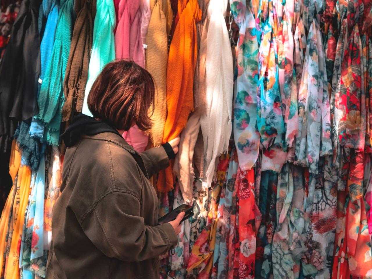 Woman at market stall looking at colored scarves