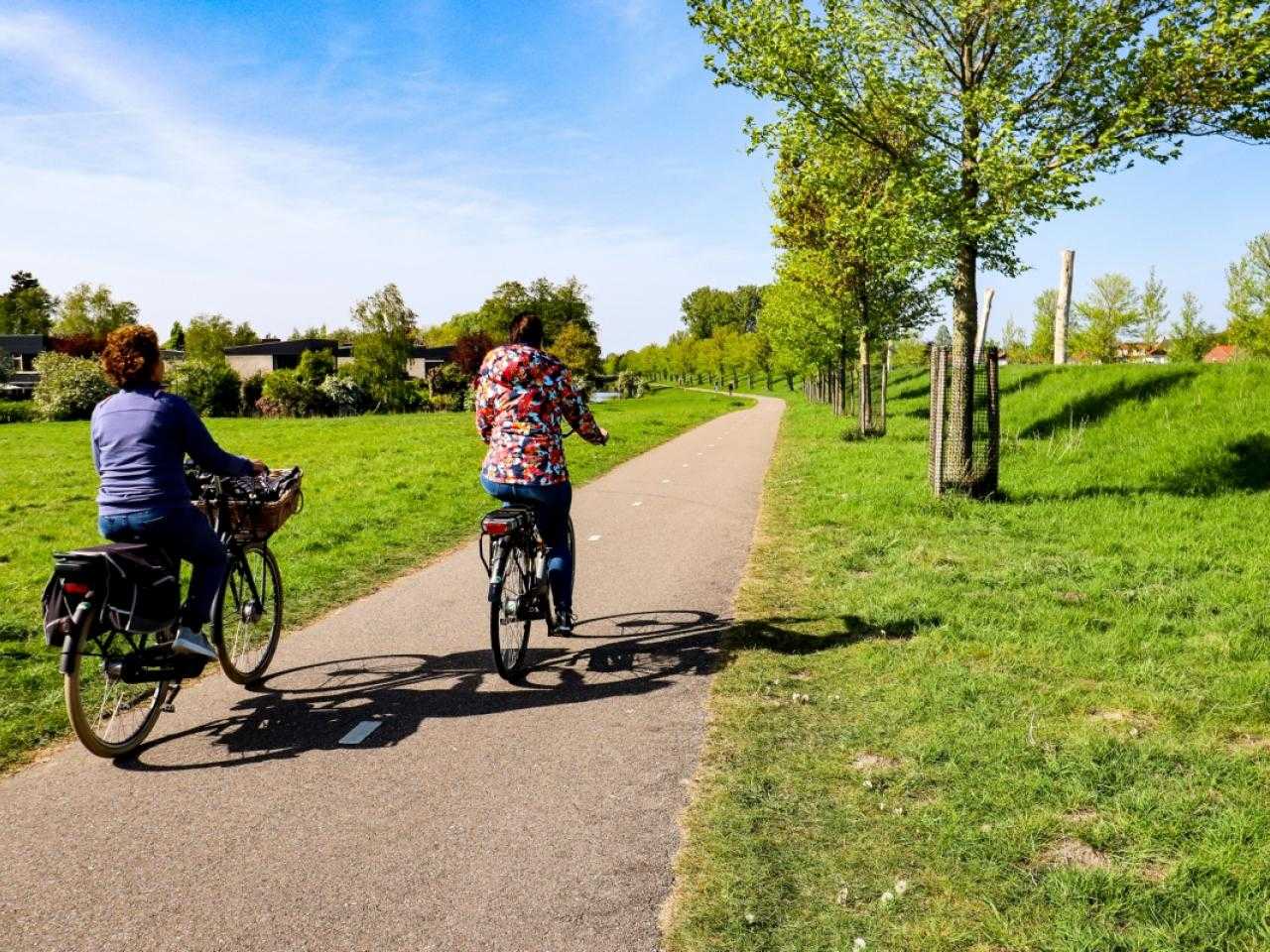 Twee mensen op de fiets door een weiland
