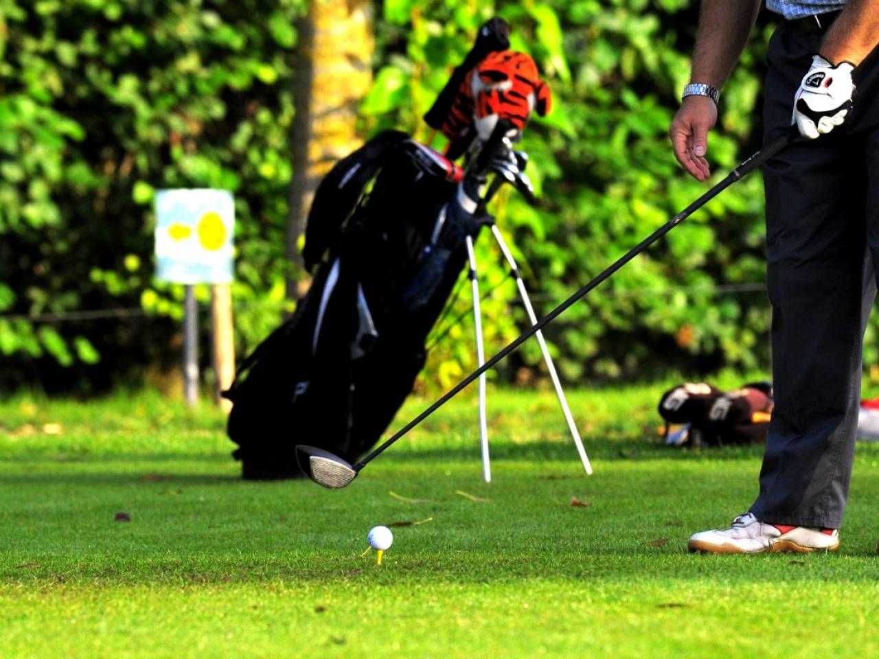 Golfer ready to hit with golf bag in the background