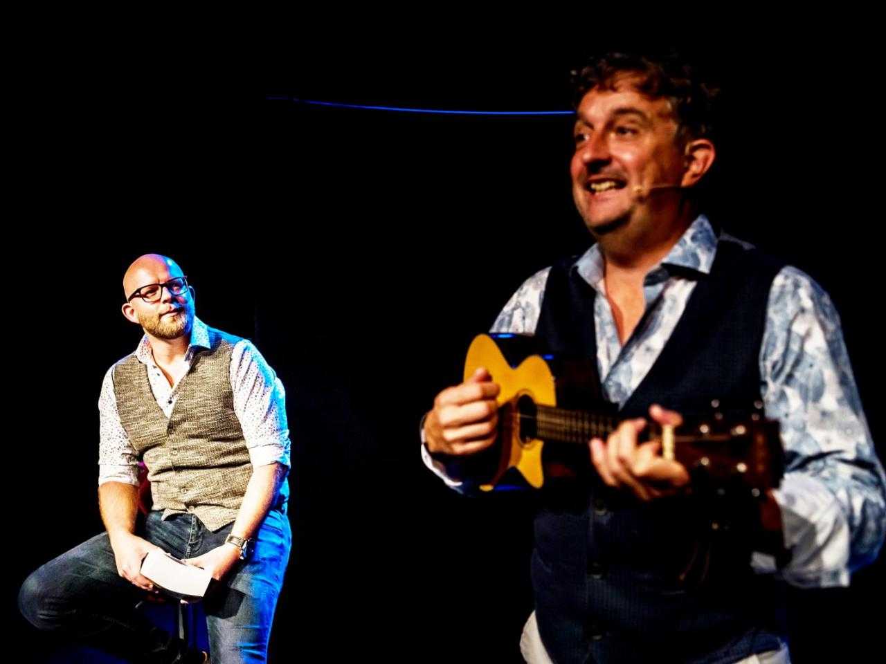 De geld gasten op een kruk en met ukulele.