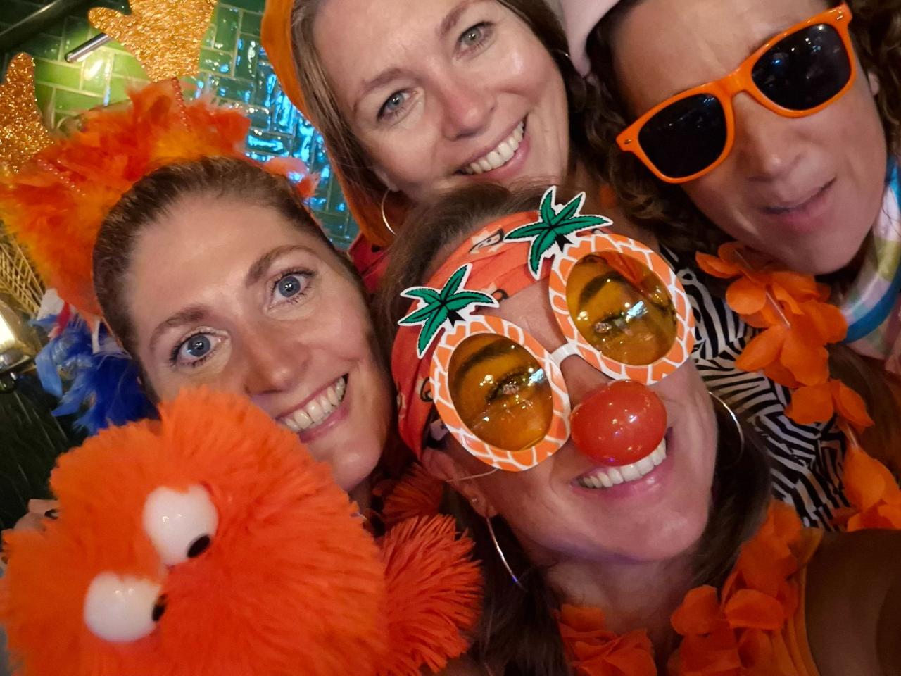 Groepsfoto van een team, in oranje gekleed, tijdens de muziekbingo
