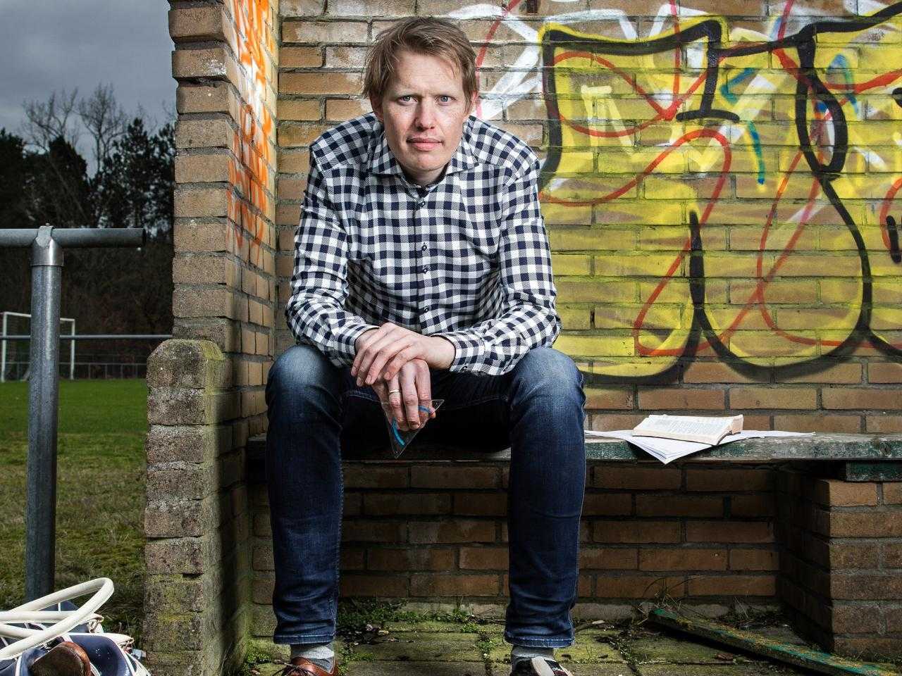 Jan Beuving voor een graffitimuur op een bankje.