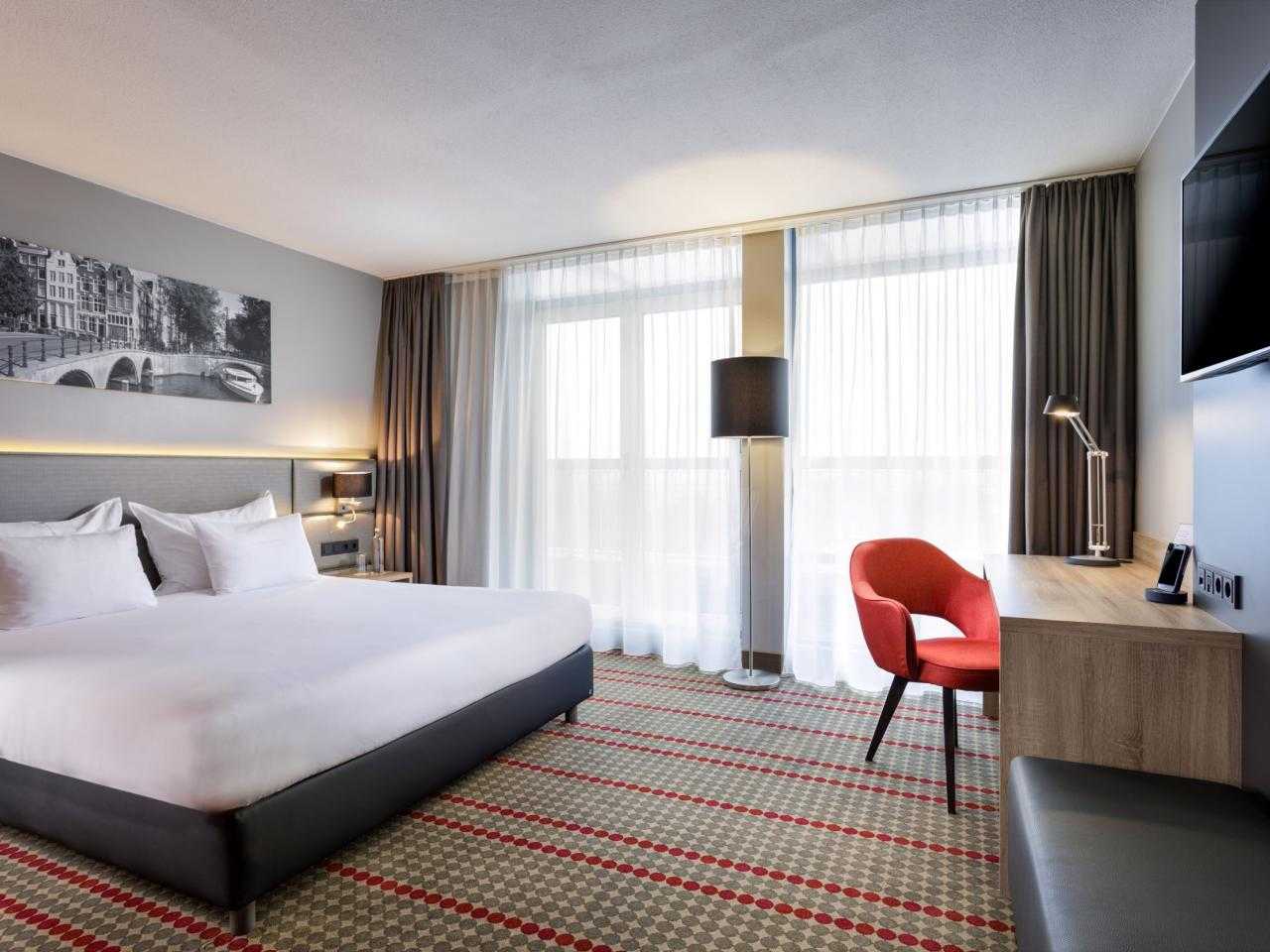 Interieur hotelkamer met met bureau en rode stoel Ramada hotel