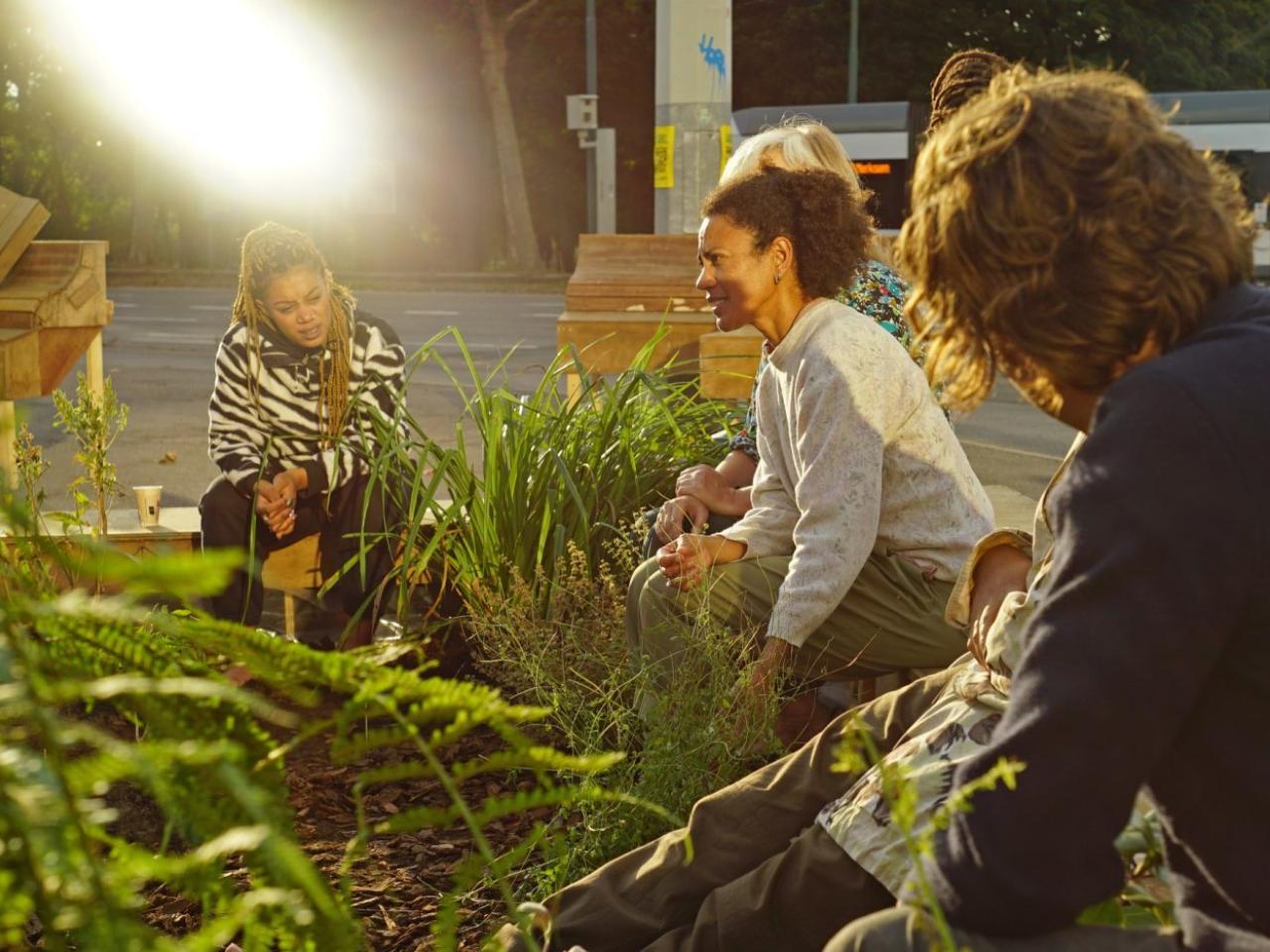 Vier mensen zitten samen in een groene tuin