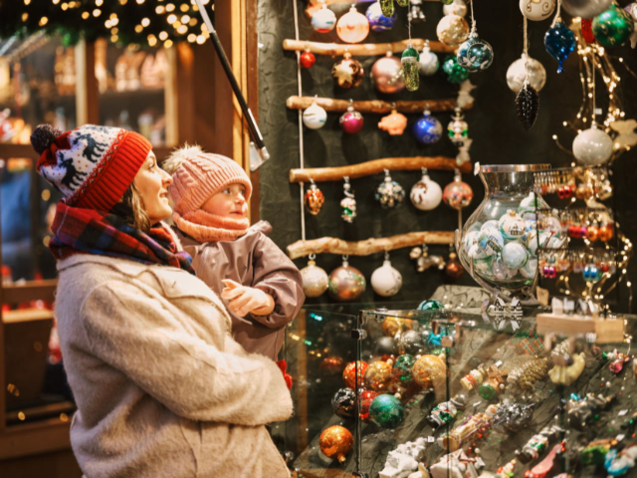 Vrouw en kind voor een versierde kerstkraam