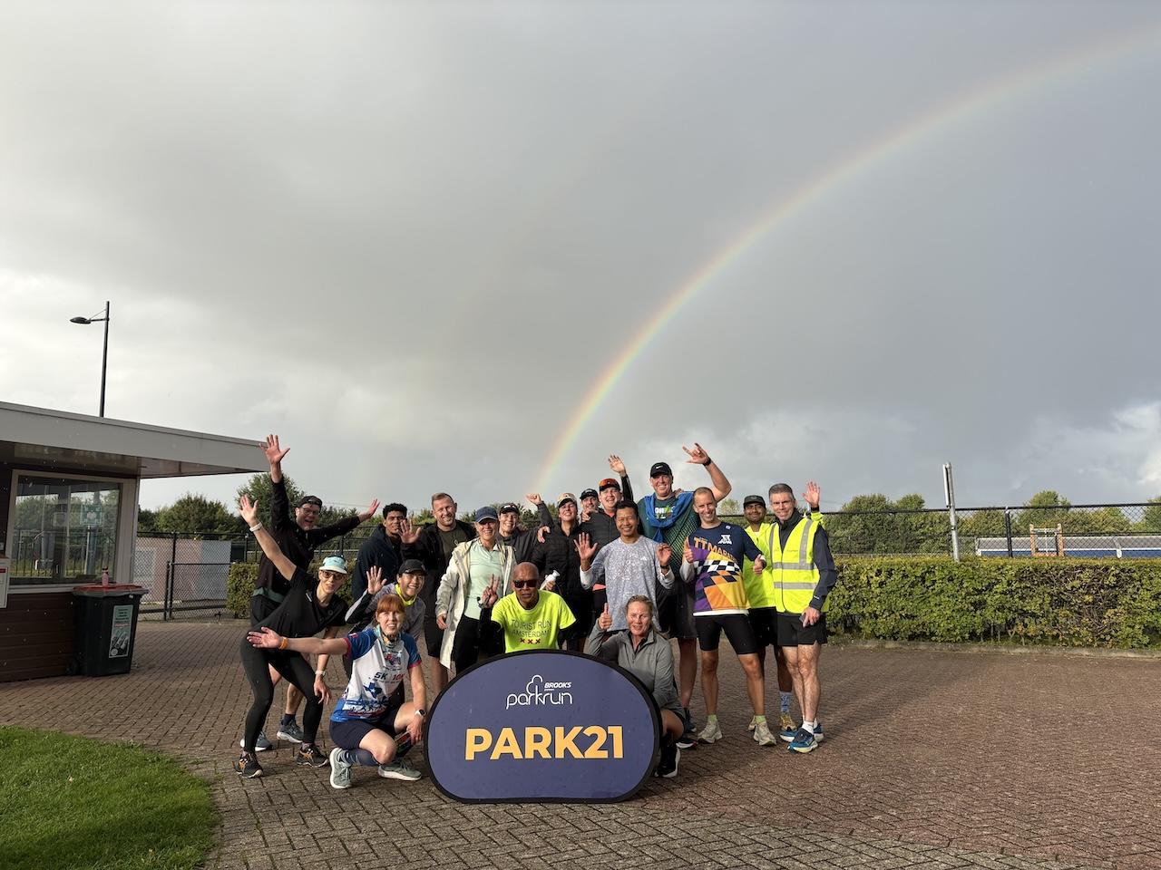 Groep hardlopers tijdens een parkrun met regenboog