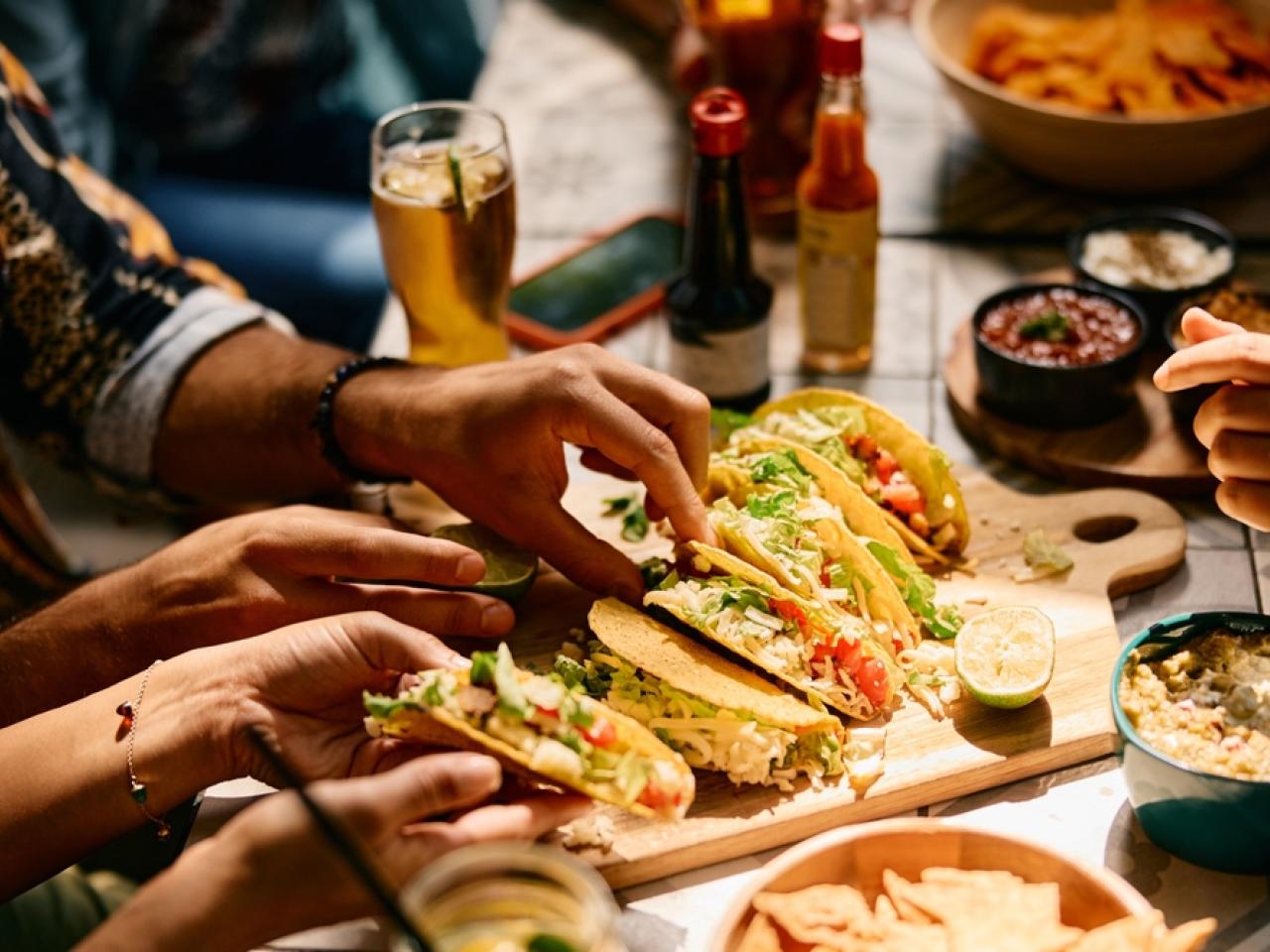 Variatie aan Mexicaanse gerechten op tafel met mensen eromheen