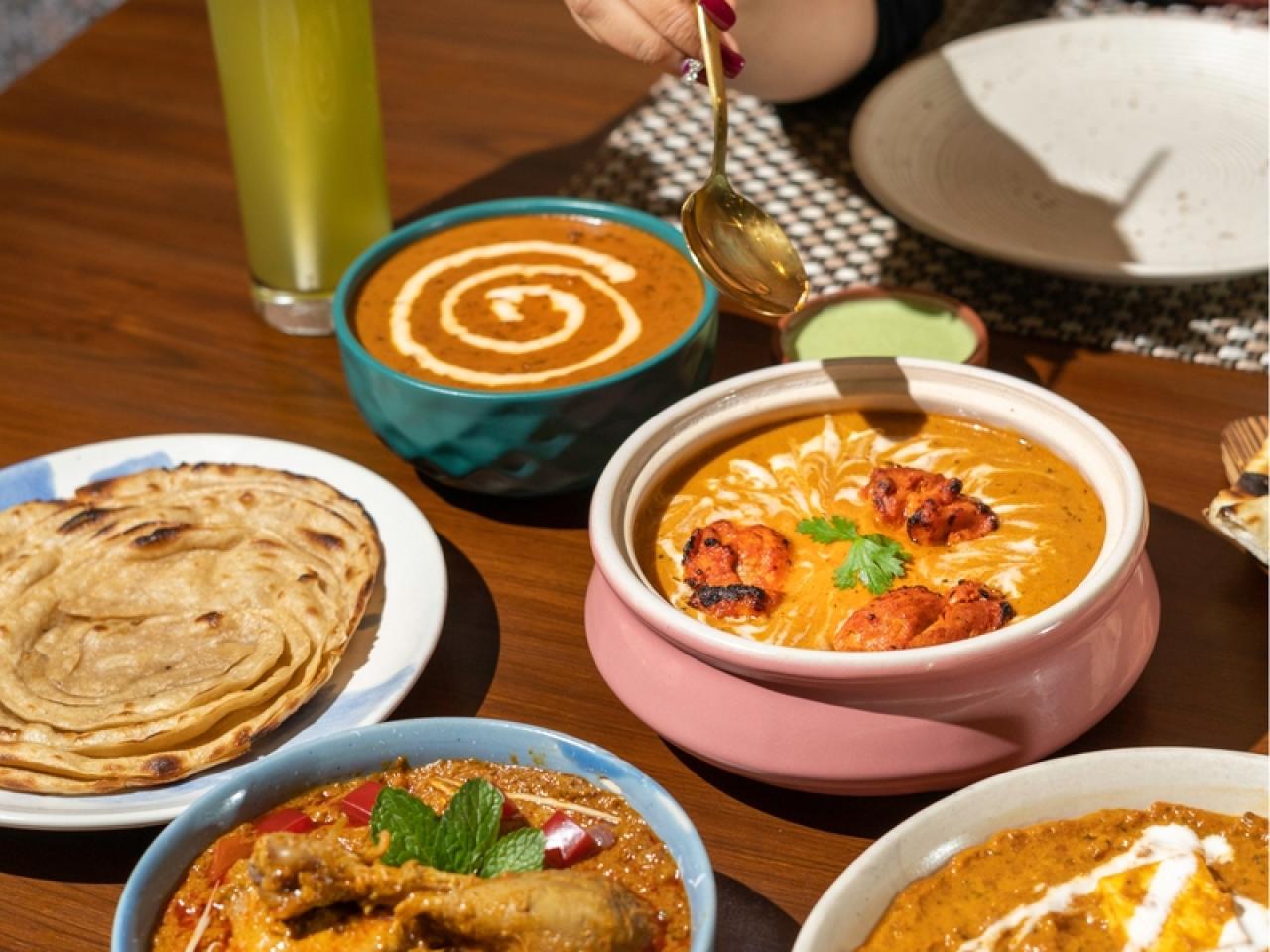 tafel gevuld met Indiase gerechten op kleurrijke borden